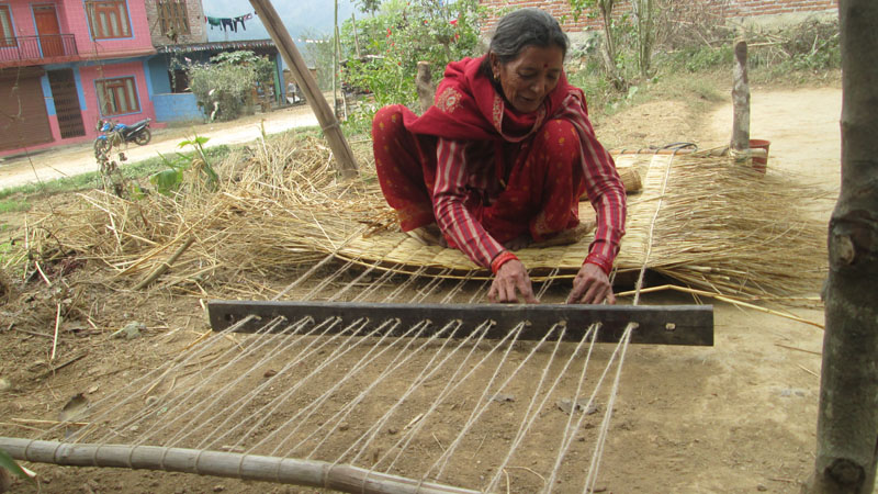 A woman of Barabote-6 in Byas Municipality of Tanahun district weaves hay into a mattress, on Monday, February 1, 2016. Photo: Madan Wagle
