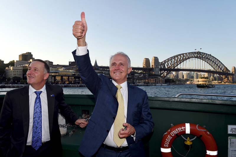 Australian Prime Minister Malcolm Turnbull (right) waves to supporters as he travels with New Zealand counterpart John Key on a ferry in front of the Sydney Harbour Bridge in Sydney, Australia, on February 19, 2016. Photo: Reuters