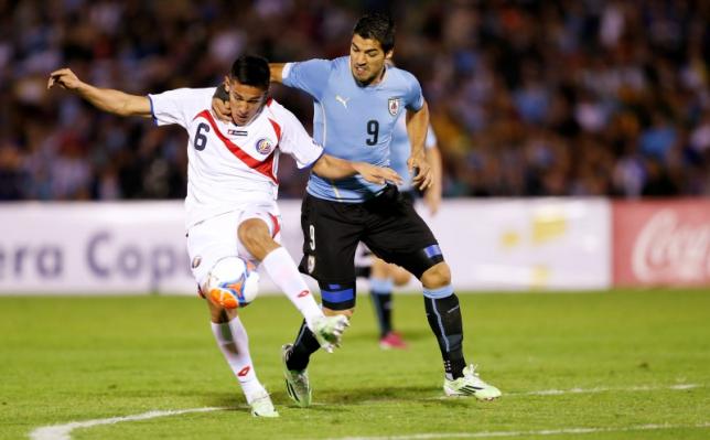 Luis Suarez of Uruguay struggles for the ball with Oscar Duarte (L) of Costa Rica during a friendly match in Montevideo, November 13, 2014. REUTERS/Andres Stapff