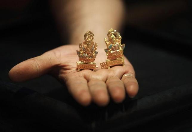 A worker at a jewellery showroom displays gold idols of Hindu elephant god Ganesh (L) and Hindu goddess Lakshmi in Kolkata August 30, 2013. REUTERS/Rupak De Chowdhuri/Files