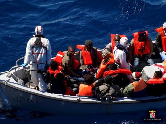 Migrants sit on a rescue boat during a rescue operation of migrants by Italian Navy vessels in this March 18, 2016 handout picture provided by Marina Militare. REUTERS/Marina Militare/Handout via Reuters