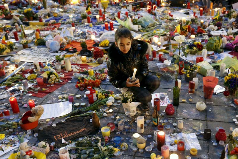 A girl lights a candle as people pay tribute to the victims of Tuesday's bomb attacks at the Place de la Bourse in Brussels, Belgium, on March 26, 2016. Photo: Reuters