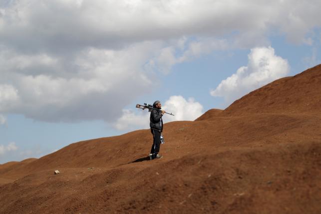 A rebel fighter from 'Jaysh al-Sunna' holds his weapon as he stands behind a sand barricade in Tel Mamo village, in the southern countryside of Aleppo, Syria March 6, 2016. REUTERS/Khalil Ashawi