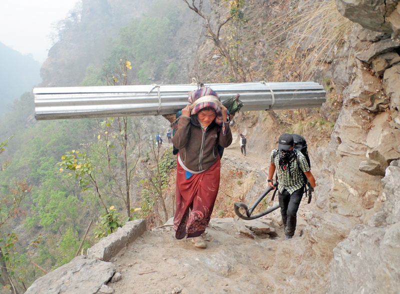 A local woman carrying Zinc sheets on her back along the Manalsu trekking trail in Lipubhir, Gorkha district , on Sunday, March 27, 2016. Photo: RSS