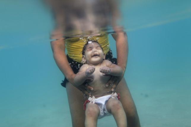 Rosana Vieira Alves and her 5-month-old daughter Luana Vieira, who was born with microcephaly, pose for a picture in the sea of Porto de Galinhas, a beach located in Ipojuca, in the state of Pernambuco, Brazil, March 2, 2016. REUTERS/Ueslei Marcelino