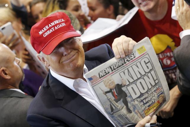 U.S. Republican presidential candidate Donald Trump holds up the front page of the New York Post as he signs autographs at a rally with supporters in Harrington, Delaware, U.S. April 22, 2016. REUTERS/Jonathan Ernst