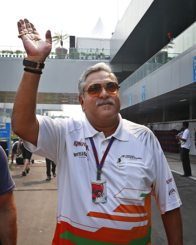 FILE- Force India team principal and businessman Vijay Mallya waves as he walks down the F1 paddock after the third practice session for the Indian Formula One Grand Prix at the Buddh International Circuit in Noida, on the outskirts of New Delhi, India, on October 27, 2012. Photo: Saurabh Das/AP