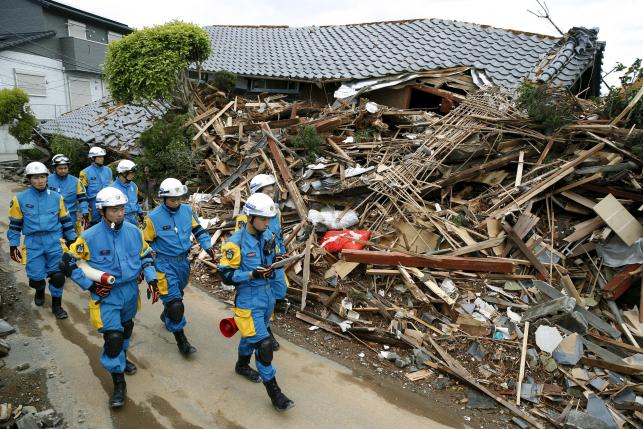 Police officers check a collapsed house after an earthquake in Mashiki town, Kumamoto prefecture, southern Japan, in this photo taken by Kyodo April 17, 2016.  REUTERS/Kyodo