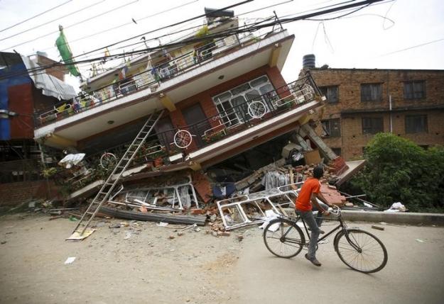 A boy riding a bicycle looks at a collapsed house after Saturday's earthquake, in Kathmandu, Nepal April 28, 2015. REUTERS/Navesh Chitrakar