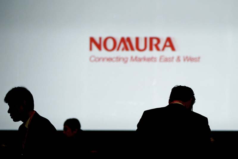 Investors stand in front of a screen showing the logo of Nomura Holdings Inc in Tokyo, Japan, on December 1, 2015. Photo: Reuters/ File