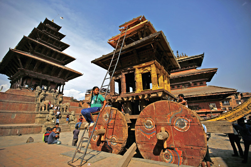 A schoolgirl sitting on a ladder as a chariot is being constructed for Bisket Jatra festival, in Bhaktapur, on Wednesday. During the festival, ndevotees pull the chariot carrying a statue of Lord Bhairav to celebrate the start of the Nepali New Year. Photo: THT
