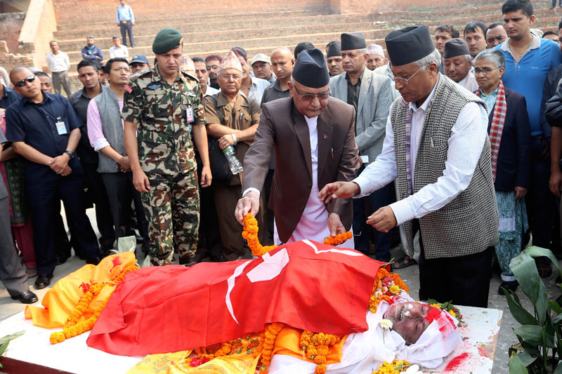 Prime Minister and CPN-UML Chairman KP Sharma Oli draps the party flag over the body of Ram Prasad Sharma at Nepal Academy in the Capital on Saturday, April 30, 2016. Photo: RSS 