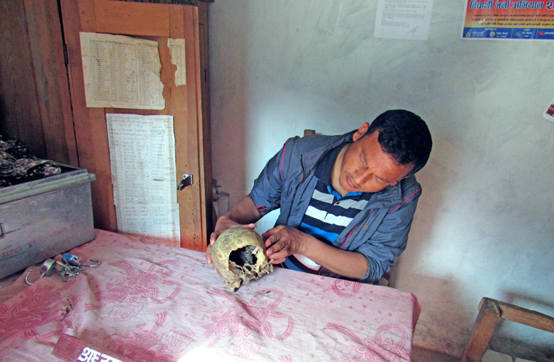 CPN-UML publicity department chief Ambar Khadka looking at the skull of Tara Chandra Regmi at the party office, in Bajura, on Friday, April 22, 2016. Photo: Prakash Singh