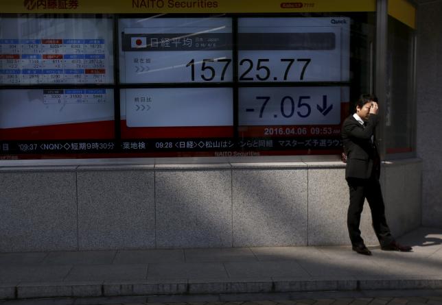 A businessman wipes his face as he stands in front of electronic boards showing the Japan's Nikkei average outside a brokerage in Tokyo, Japan April 6, 2016. REUTERS/Issei Kato