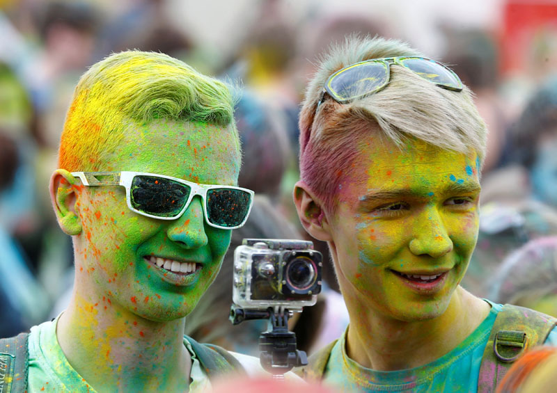 Men covered with coloured powder attend the ColorFest festival.