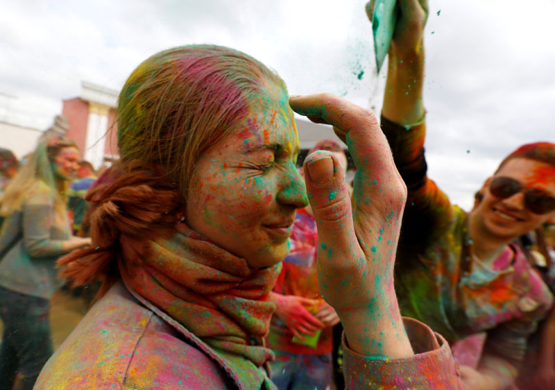 A man covers a woman with coloured powder.