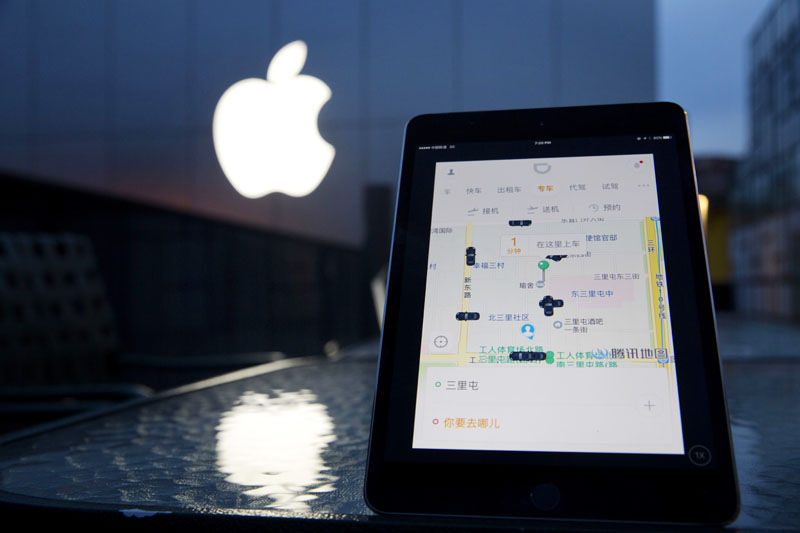 A mobile device displaying the Didi Chuxing app is posed near the Apple store logo in Beijing, China, on Friday, May 13, 2016. Photo: Ng Han Guan/AP