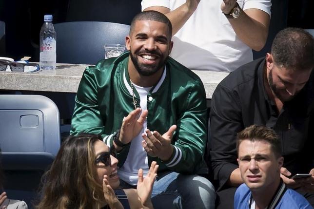 Musician Drake applauds as his image is displayed on the TV monitors during the Serena Williams, Roberta Vinci match at the U.S. Open Championships tennis tournament in New York, September 11, 2015. REUTERS/Carlo Allegri