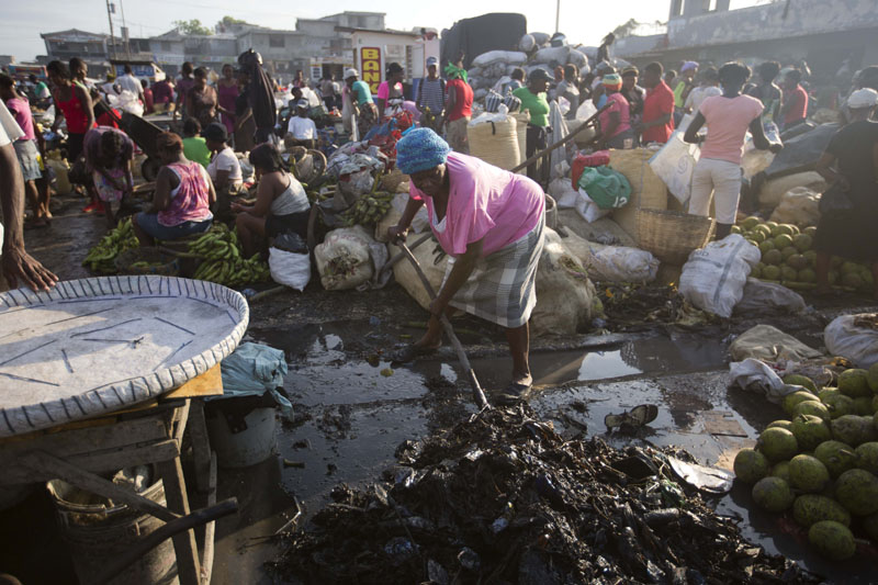 A vendor shovels rubbish away from her stand at a street market in Port-au-Prince, Haiti, on Saturday, May 21, 2016. New research suggests that the Zika virus has been present in Haiti since 2014. Photo: AP