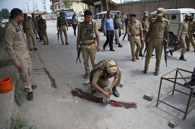 An Indian policeman cleans the ground where police officers were killed when suspected rebels fired at a group of police in Srinagar, Indian controlled Kashmir, Monday, May 23, 2016. Indian security forces are searching the area for the assailants who fled after the attack. Photo: Dar Yasin/AP