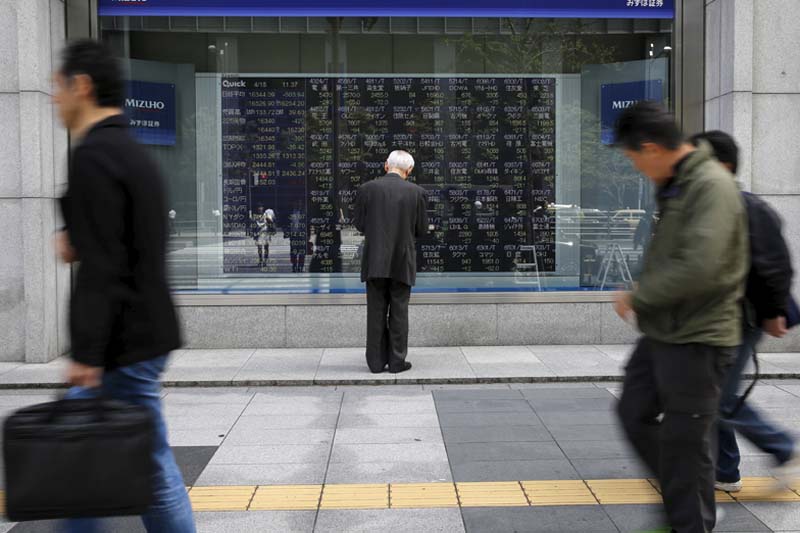 A man looks at a stock quotation board outside a brokerage in Tokyo, Japan, on April 18, 2016. Photo: Reuters