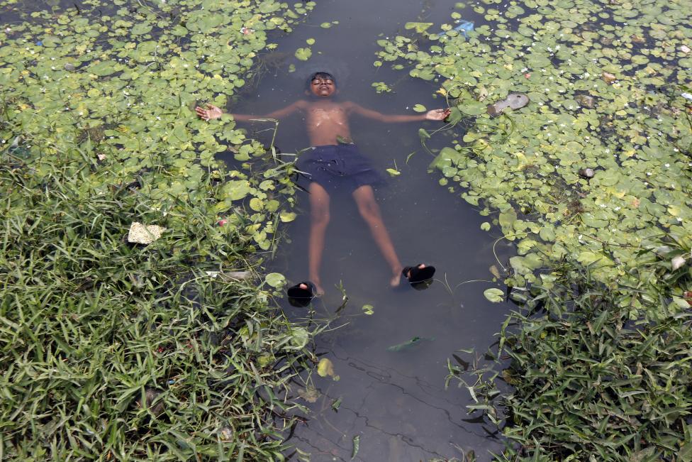 A boy floats in a pond to cool off on a hot summer day on the outskirts of Kolkata, India, April 28, 2016. REUTERS/Rupak De Chowdhuri