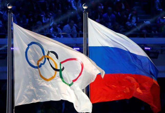 The Russian national flag (R) and the Olympic flag are seen during the closing ceremony for the 2014 Sochi Winter Olympics, Russia, February 23, 2014.  REUTERS/Jim Young/File Photo