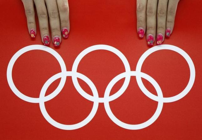 A volunteer's nails are seen beside the Olympic rings during the women's 5,000 metres speed skating race at the Adler Arena in the Sochi 2014 Winter Olympic Games February 19, 2014. REUTERS/Issei Kato/Files