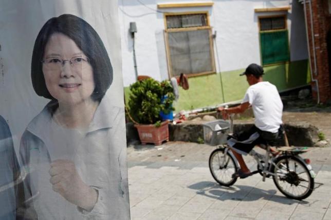 A man rides a bicycle past a flag with the image of Taiwan president-elect Tsai Ing-wen in Pingtung, Taiwan April 27, 2016. Picture taken April 27, 2016. REUTERS/Tyrone Siu