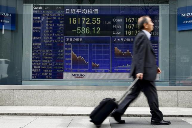 A man walks past an electronic board displaying the Nikkei average outside a brokerage in Tokyo, Japan, April 1, 2016. REUTERS/Thomas Peter