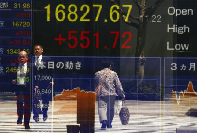 People are reflected in a screen displaying the Nikkei average outside a brokerage in Tokyo, Japan April 19, 2016. REUTERS/Thomas Peter