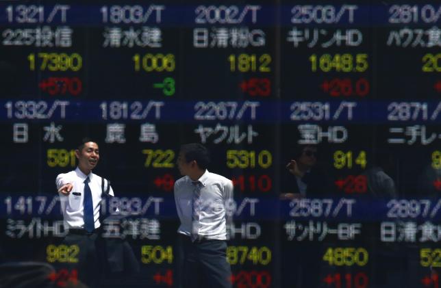 Men are refelcted in a screen displaying market indices outside a brokerage in Tokyo, Japan April 19, 2016. REUTERS/Thomas Peter
