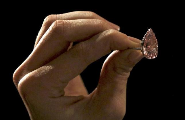 An assistant poses with a 15.38 carat vivid pink diamond at Sotheby's auction house in London, Britain April 7, 2016. REUTERS/Neil Hall/Files