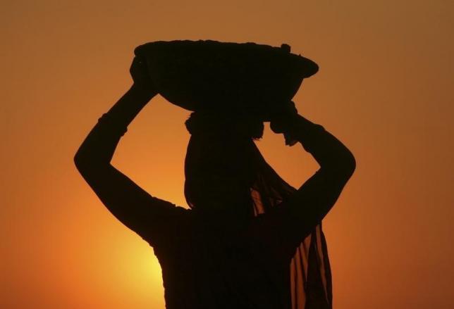 A woman labourer carrying cement is silhouetted against the setting sun at the site of a commercial complex on the outskirts of Jammu November 22, 2012. REUTERS/Mukesh Gupta