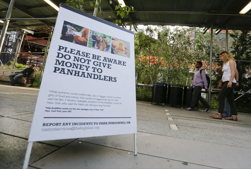 Pedestrians pass a warning sign on panhandlers on The High Line, one of New York City's most visited attractions, on Wednesday, June 22, 2016. Photo: AP