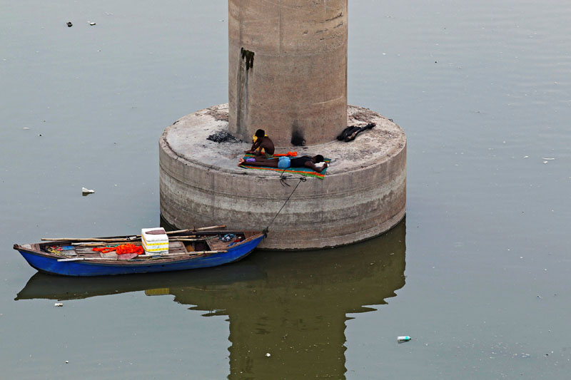 Men rest on a pillar of a bridge over the river Ganga on a hot summer day in Allahabad, India, on Saturday June 25, 2016. Photo: Reuters