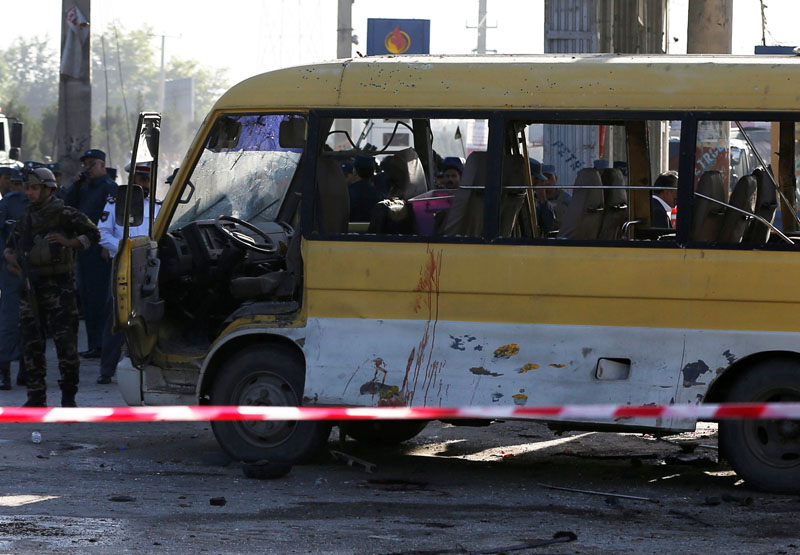 Afghan security forces inspect the damage of a minibus that was hit in a suicide attack in Kabul. AP