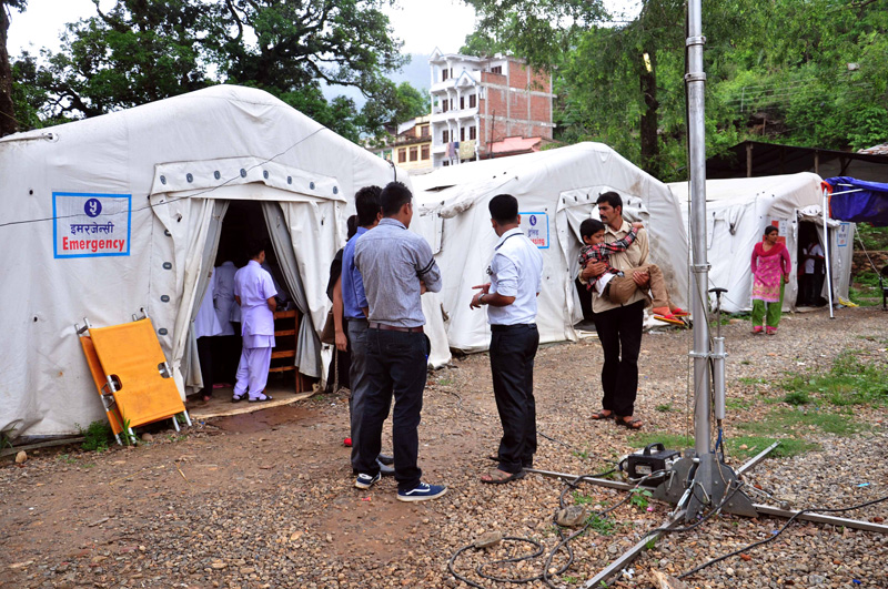 A man takes his son to the Nuwakot District Hospital, which is being run in tents after the April 2015 earthquake, as others look on at Trishuli of Nuwakot, on Monday, June 20, 2016. The hospital building had collapsed in the devastating earthquake that killed at least 1000 people in the district alone. The hospital, however, is being shifted to  a new prefab building within few days. Photo: Bal Krishna Thapa