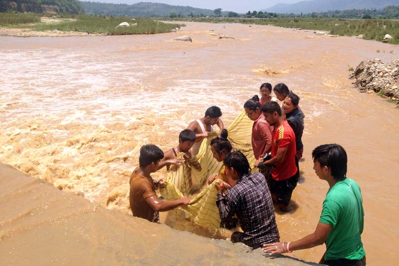 Youth try to fish using a net in the Karra River of Hetaunda in Makawanpur district, on Tuesday, June 21, 2016. Torrential rain today resulted in flood in many districts of the country. Photo: Prakash Dahal