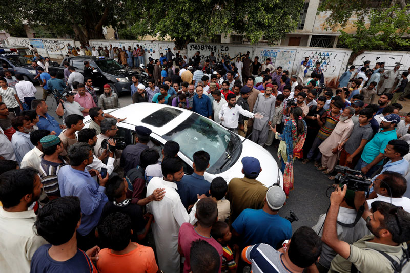 Onlookers and journalists gather around the car driven by Sufi singer Amjad Sabri, who was killed when unidentified gunmen shot at his car, in Karachi, Pakistan, June 22, 2016. Photo: Reuters/File