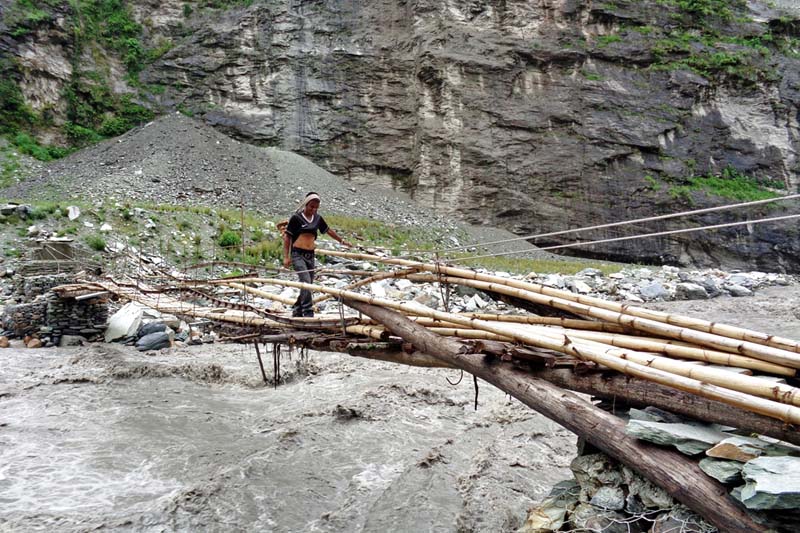 A local crossing a temporary bridge made of bamboo over the Kaligandaki River, in Baisari of Myagdi, on Saturday, June 25, 2016. Delay in reconstruction of the suspension bridge destroyed last year after the landslide has made transportation hard for the locals. Photo: RSS