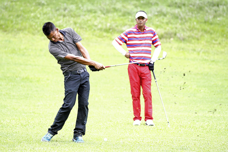 Jayaram Shrestha takes a shot as Bhuwan Nagarkoti (right) looks on waiting for his turn during the Surya Nepal NPGA Tour Championship at Gokarna Golf Club in Kathmandu on Tuesday, July 5, 2016. Photo: THT