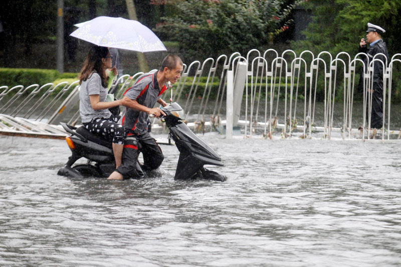 People ride along a flooded street during a heavy rainfall in Beijing, China, on July 20, 2016. Photo: Reuters