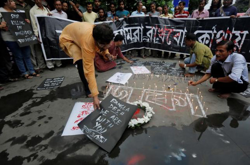 A man places a sign as others light candles during a vigil in Kolkata, India, to show solidarity with the victims of the attack at Holey Artisan restaurant after Islamist militants attacked the upscale cafe in Dhaka, Bangladesh, on July 2, 2016. Photo: Reuters