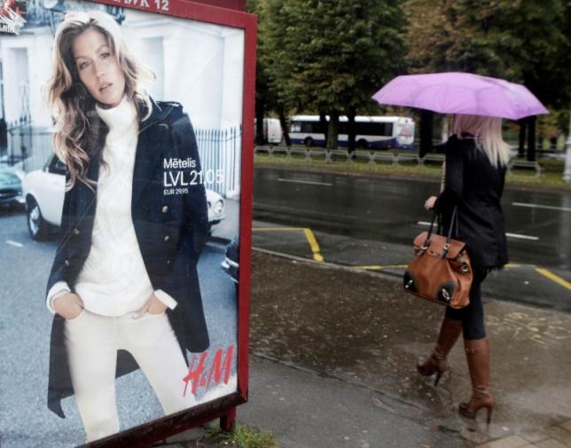 A woman walks past a H&amp;M advertisement in Riga September 25, 2013.  REUTERS/Ints Kalnins