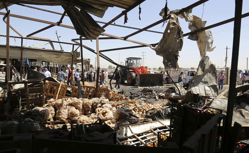 A bulldozer clears rubble at the scene of a deadly suicide car bombing at an outdoor vegetable and fruit market in a Shiite-dominated district in northeastern Baghdad, Iraq, on Tuesday, July 12, 2016. Photo: AP