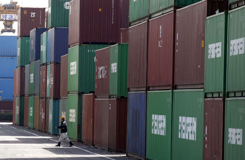 FILE - A port worker walks through the piled containers in Tokyo, on February 18, 2016 . Photo: AP