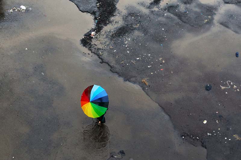 A woman carrying an umbrella crosses a flooded street as it rains in Mumbai, India on Tuesday, July 19, 2016. Photo: Reuters
