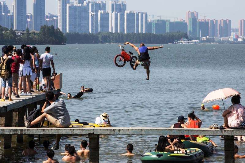 A participant jumps into a lake with a bike during a local event to call on residents to protect the  environment in Wuhan, Hubei Province, China on July 24, 2016. Photo: Reuters