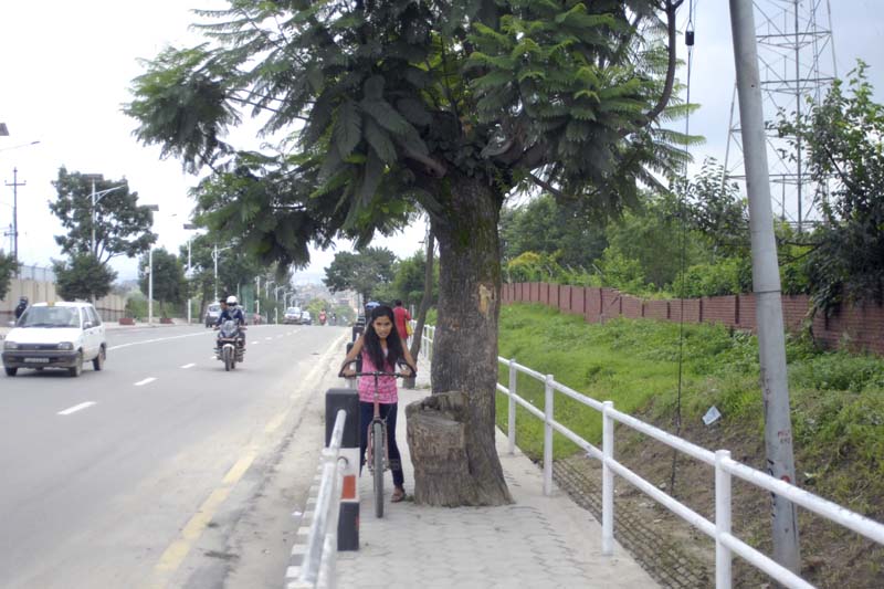 SQUEEZE: A cyclist struggles squeeze through on the footpath of Tinkune-Airport road section. Photo: Naresh Shrestha/THT